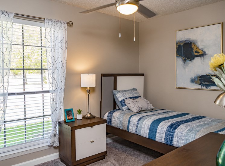 bedroom with large window, carpeting, ceiling fan, and model furnishings