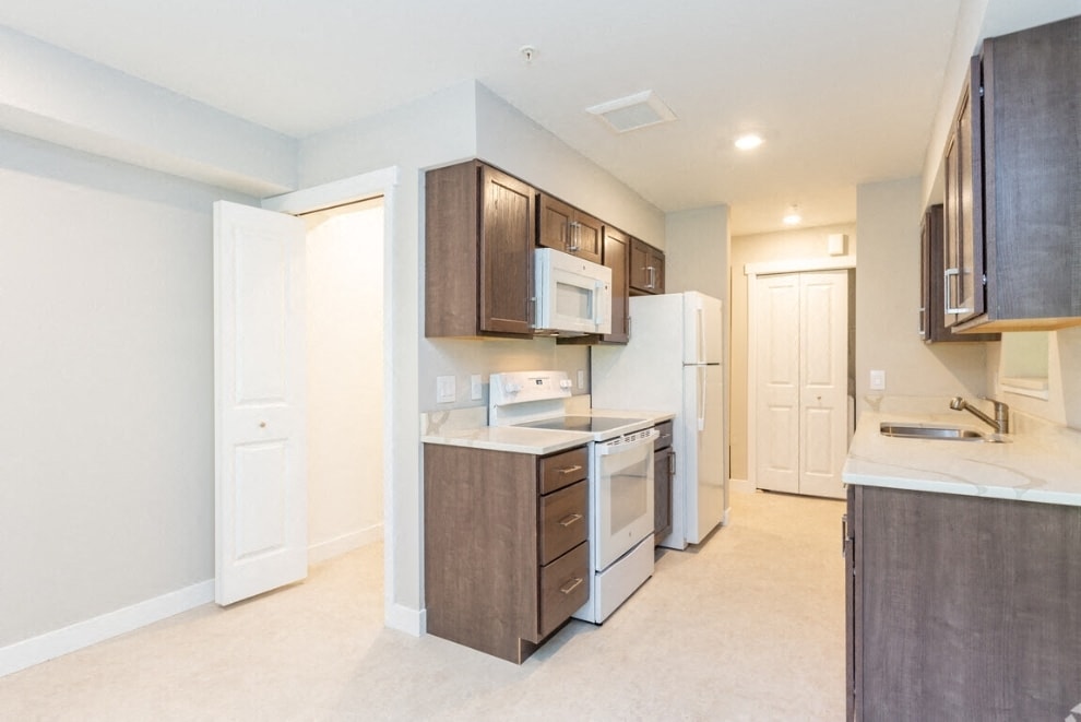 A kitchen with white appliances and brown cabinets.