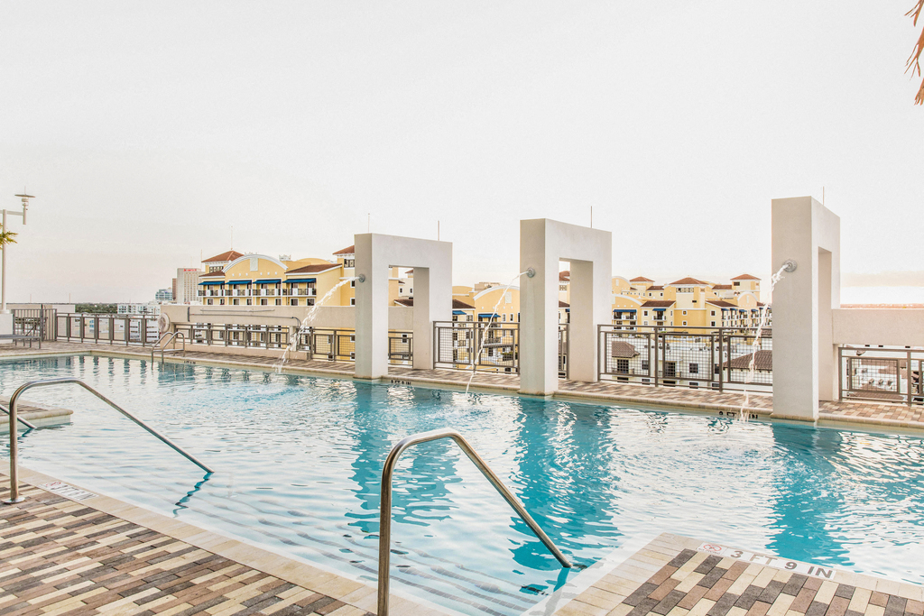 Swimming Pool with Sundeck White Decorative Fountain Feature Pouring into the Pool with Skyline in the Background