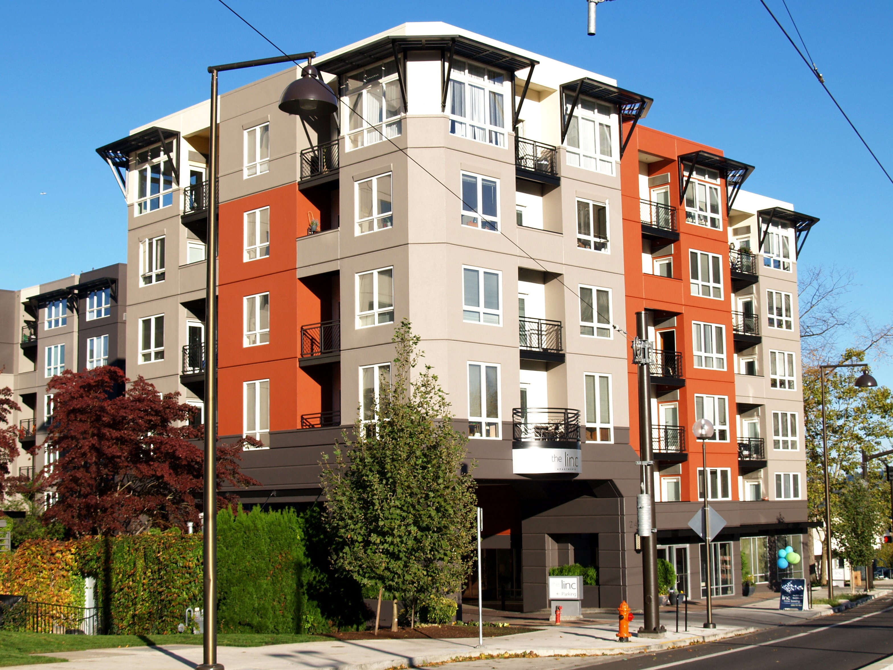 Downtown Portland OR Apartments - Linc 245 - Property Exterior with Orange, Brown, and Beige Walls, with Nearby Trees and Street View