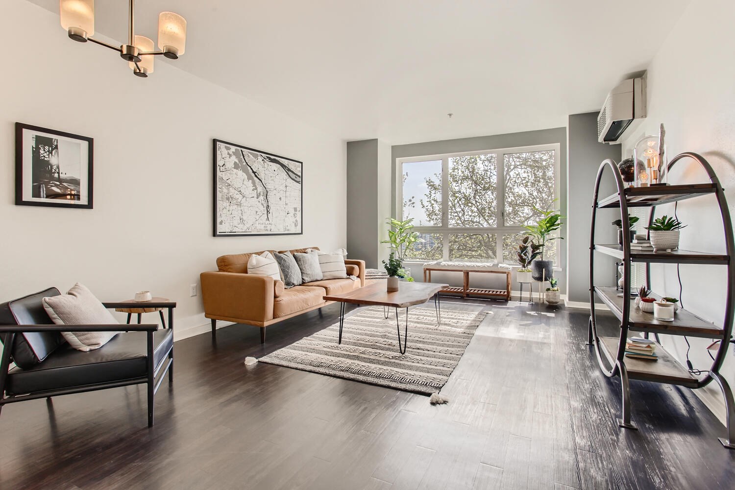 Two-Bedroom Modern Apartments in Downtown Portland, OR - Linc 245 - Living Room with Wood-Style Flooring, Couch, Armchair, Coffee Table, Wall Arts, Chandelier, and Large Windows.