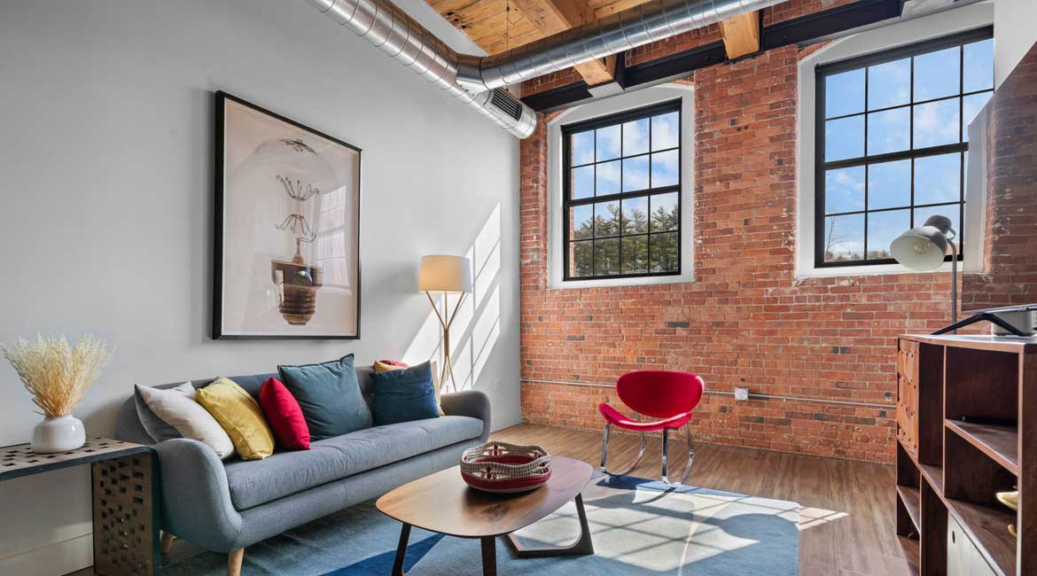 Open floor plan with exposed beams and brick
