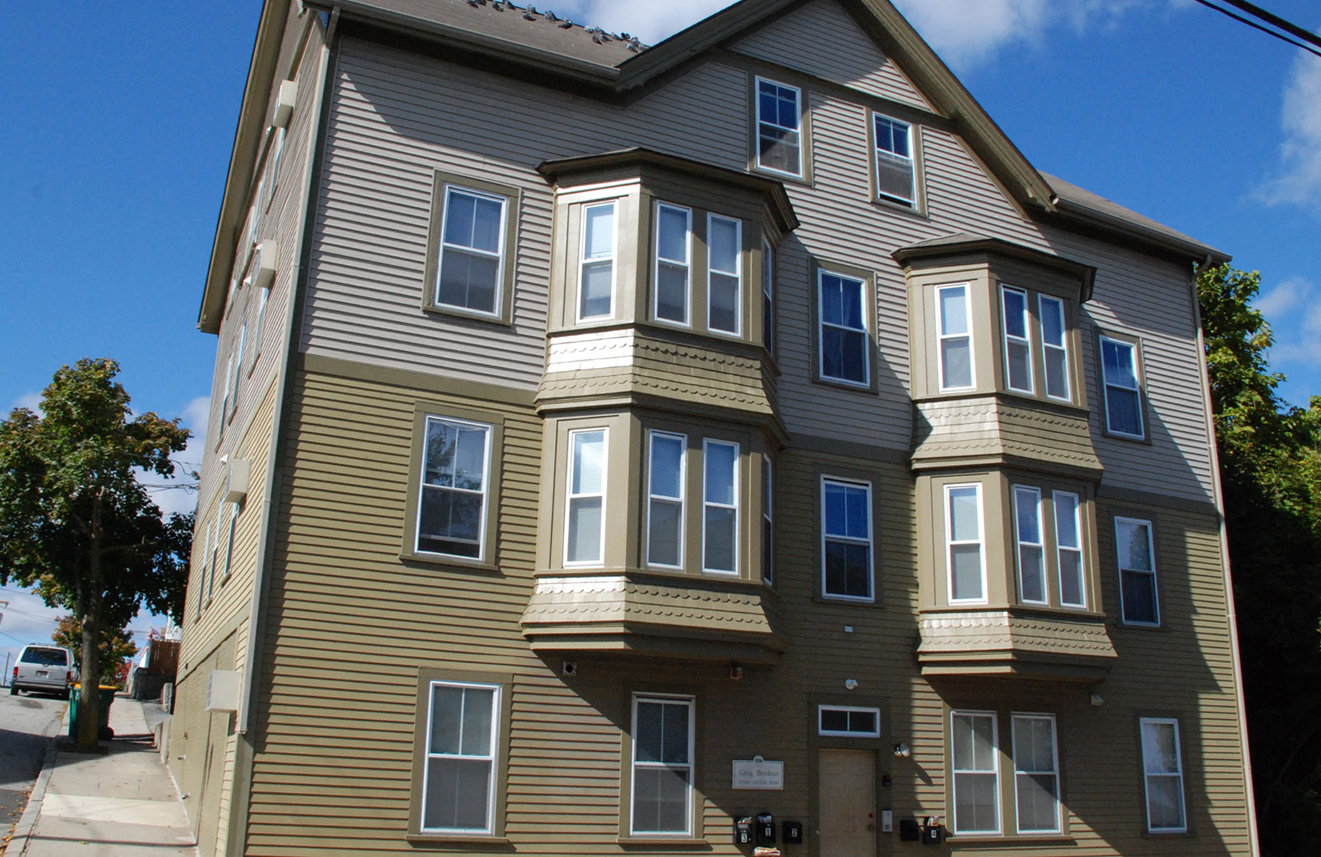 Large grey and brown house with apartments in a residential neighborhood