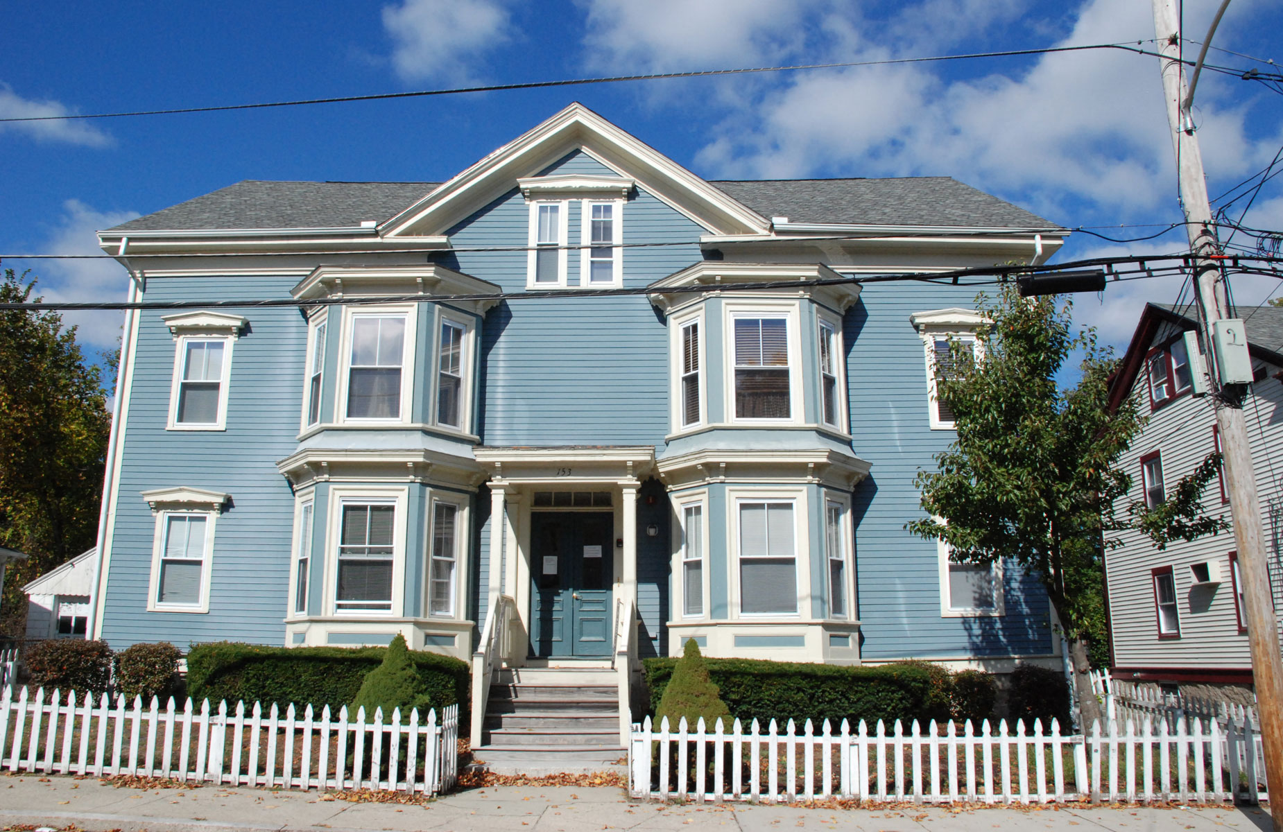 Rental apartments in a blue house with a white picket fence in a residential neighborhood