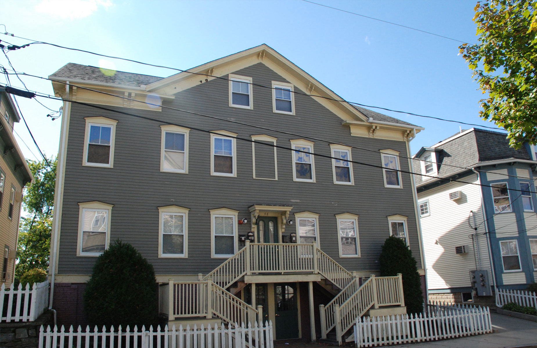 Apartments in a large grey house in a residential neighborhood