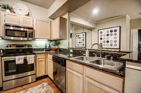 Stunning kitchen with hardwood style flooring, light colored cabinetry and stainless steel appliances