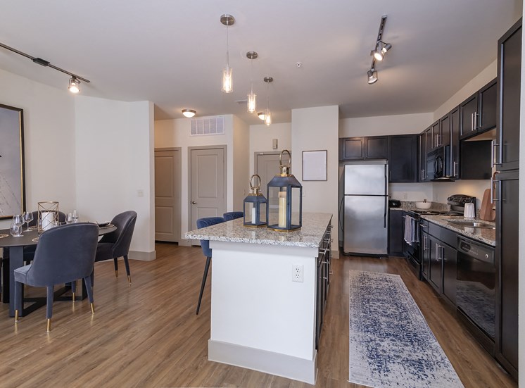 Spacious open concept kitchen with granite countertops, stainless steel appliances, and dark cabinetry.