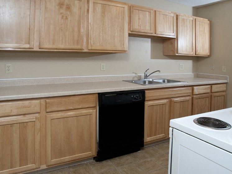 kitchen with wood cabinets, black dishwasher, white oven, and a sink