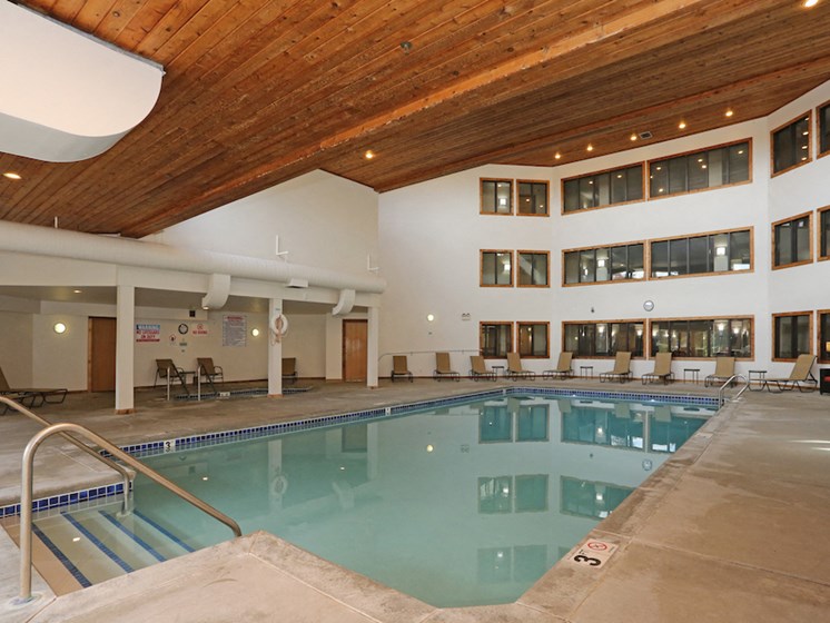 Indoor pool with high ceiling and lounge seating