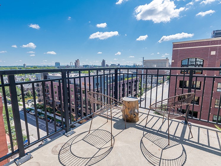 balcony with a view of downtown on a sky-blue day with two wire metal chairs