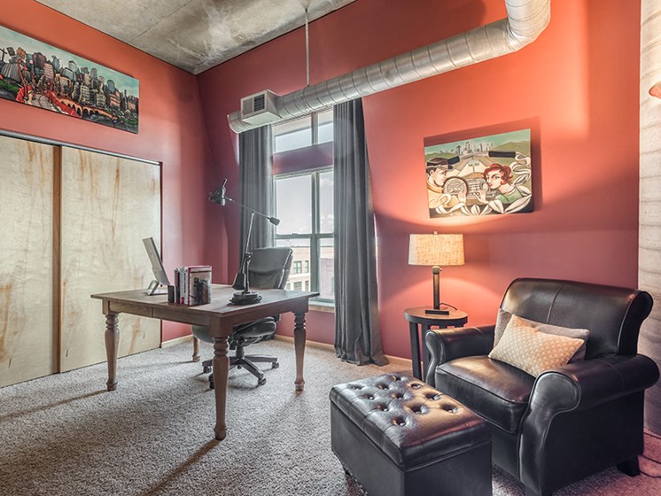 office with red walls, interesting artwork, a computer desk, and a leather recliner