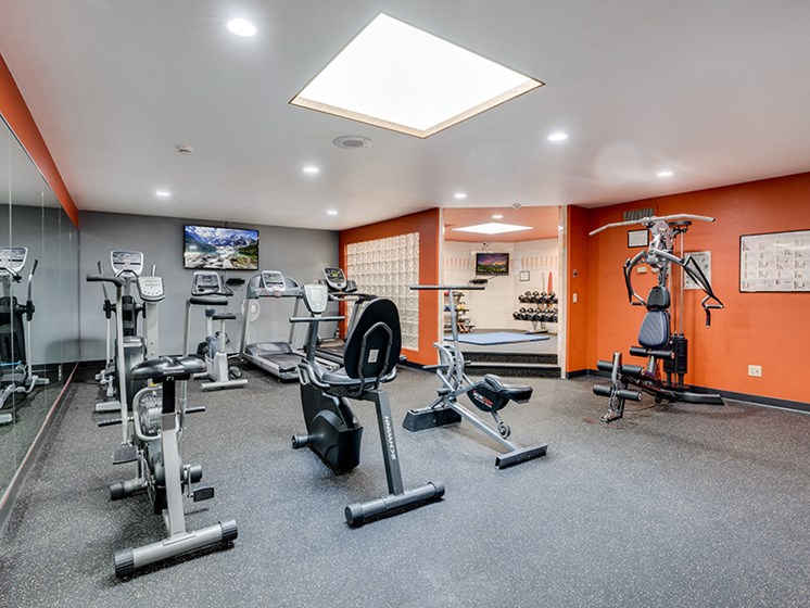 Fitness room with various equipment and orange walls