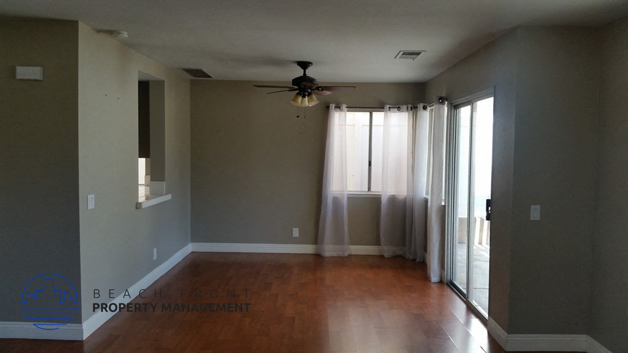 A spacious room with a ceiling fan and sliding glass doors.