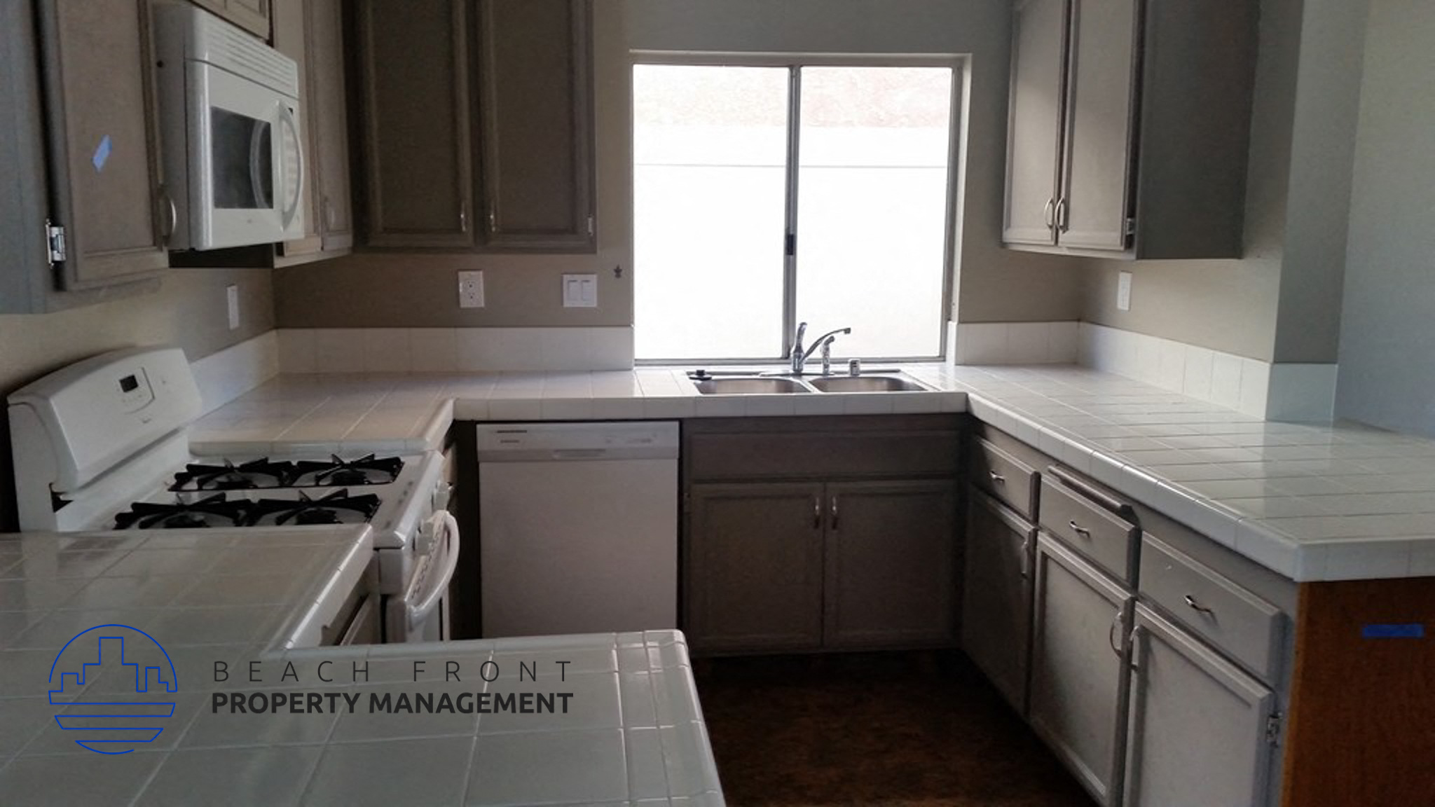 A kitchen with a stove, sink, and cabinets.