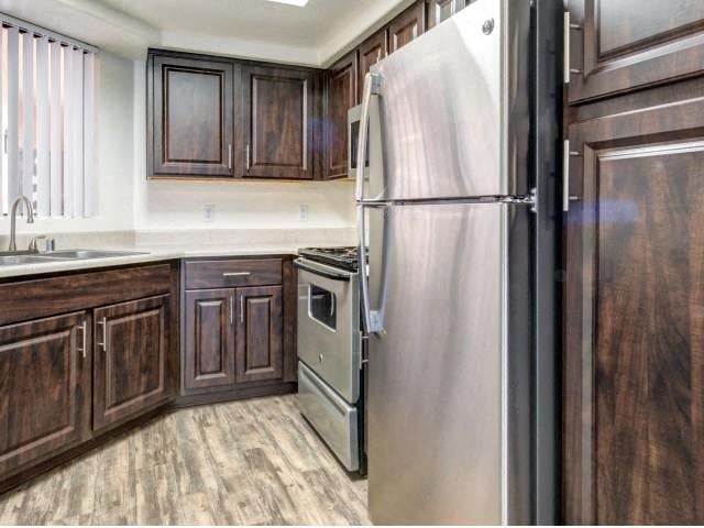 Ingleside Apartments kitchen with light brown floors, dark brown cabinets and stainless steel appliances