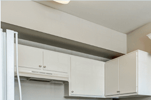 Kitchen with new black and silver Whirlpool appliances, white cabinets with brushed nickel knobs and wood-style floors