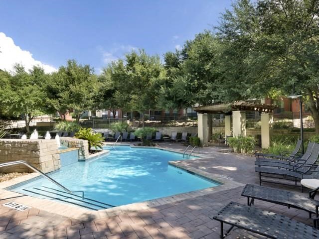 Pool surrounded by shade trees and lounge seating