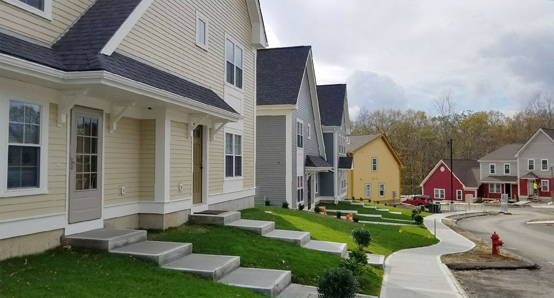 Lush, green lawns and bushes, sidewalk, and colorful homes.