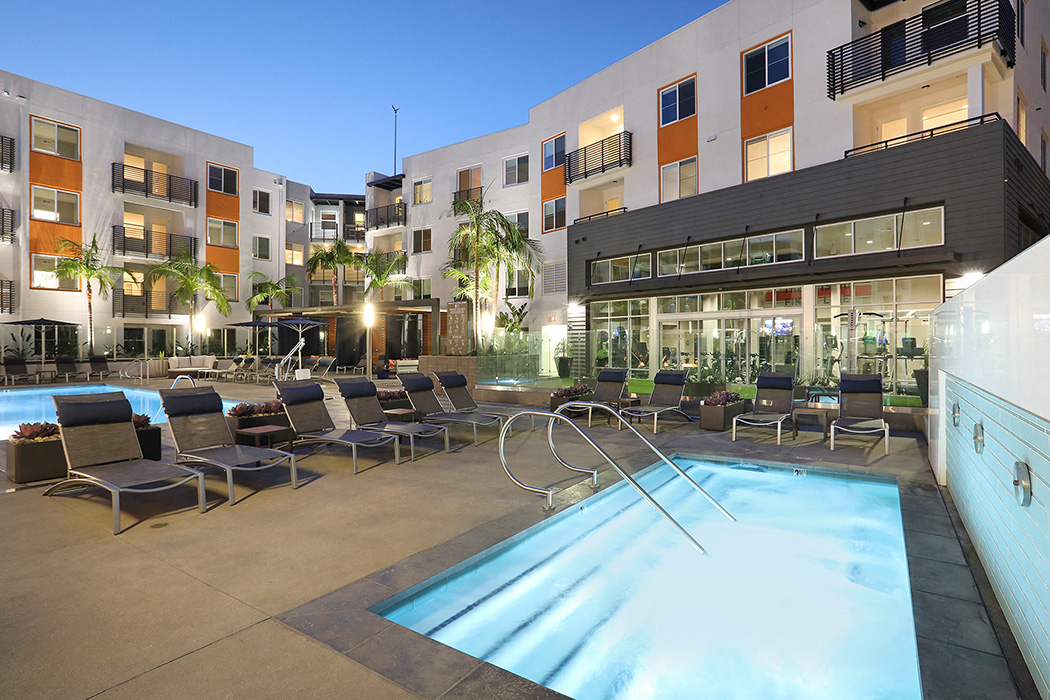 Night view of illuminated swimming pool in front of apartments at Eleven 10 in Orange, CA