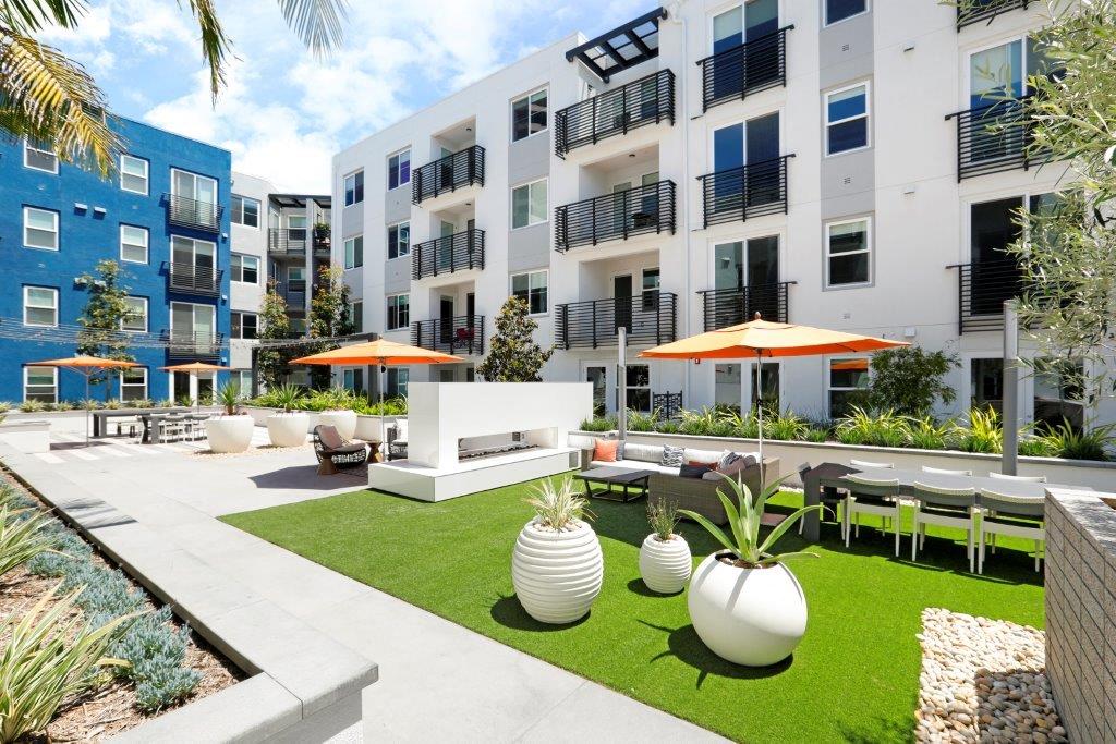 Lounge deck with tables, orange umbrellas, and green grass