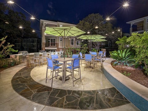 Nighttime BBQ grill patio with bar and high top umbrella covered seating