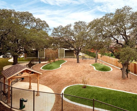 Aerial view of fenced in dog park with shaded gazebo and shade trees
