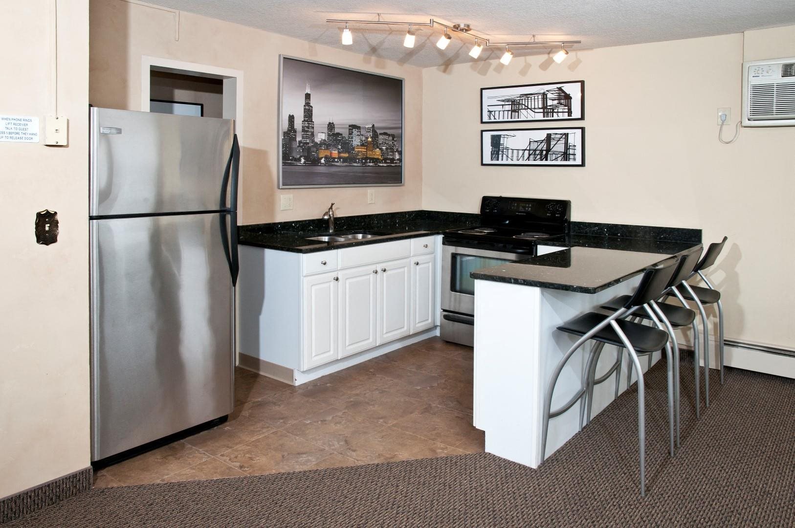 Boulevard 100 Apartments Kitchen with White Cabinetry, Black Counter Tops and Stainless Steal Appliances