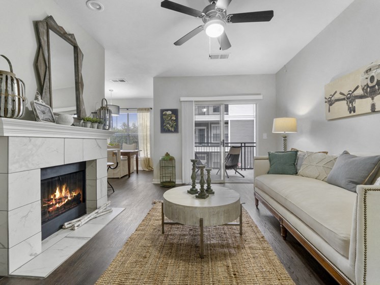 Apartments for Rent in The Colony TX - Flatiron District at Austin Ranch Cozy Living Room with a Fireplace, Stylish Decor, and Large Sliding Glass Door Leading to Private Patio