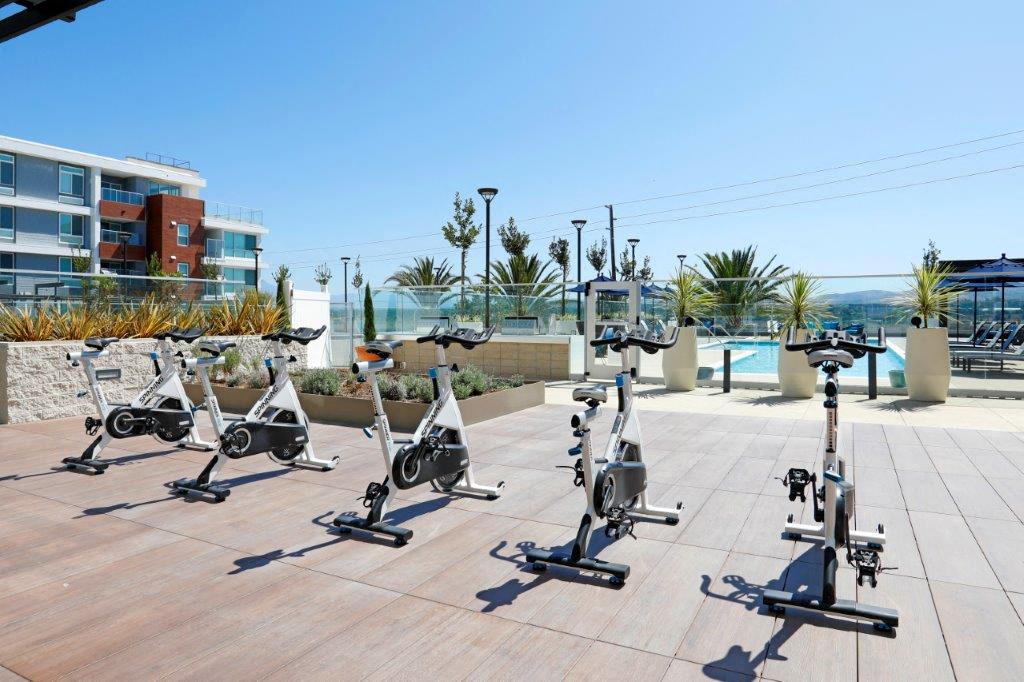 Group of exercise bikes parked on a patio near a pool