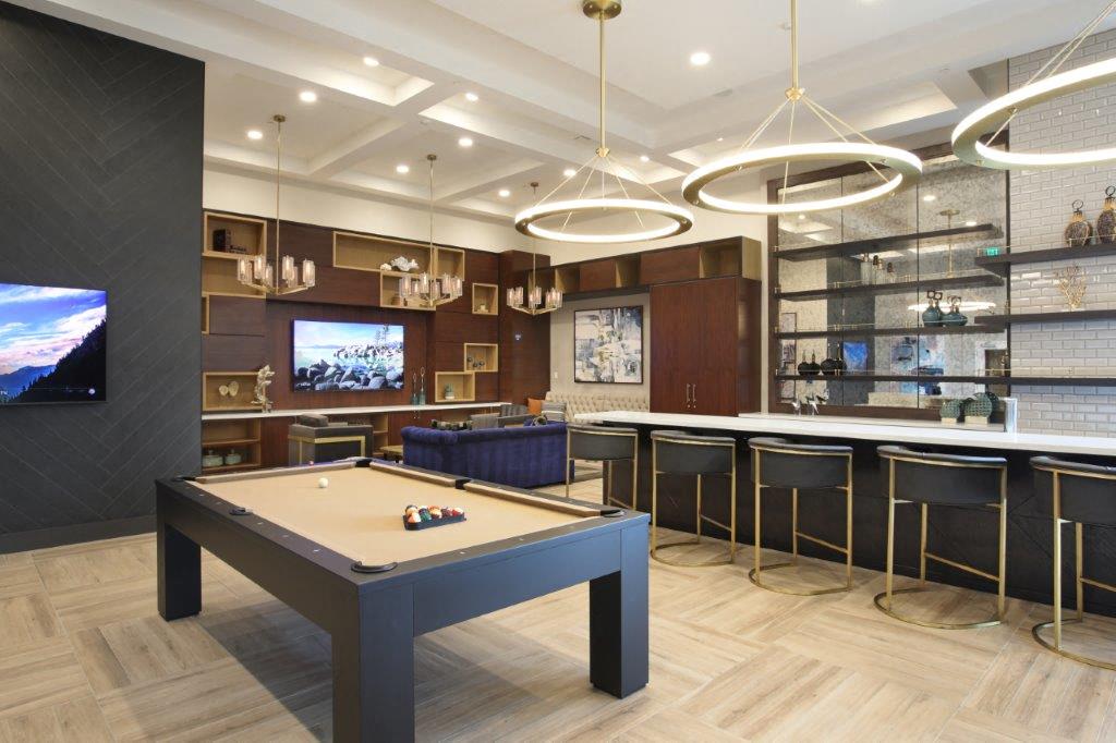 Clubhouse with pool table, bar seating, and warm finishes